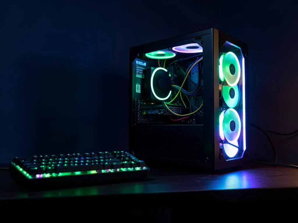 Finished custom gaming PC with green lighting beside a mechanical keyboard